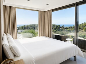 Quarto com uma cama grande, duas janelas e vista para a paisagem.