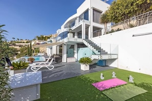 Uma casa moderna com piscina, área de estar externa e escada que dá para uma varanda.