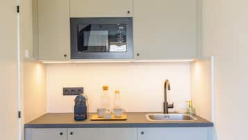 A compact kitchen with a microwave, sink, and a coffee maker.
