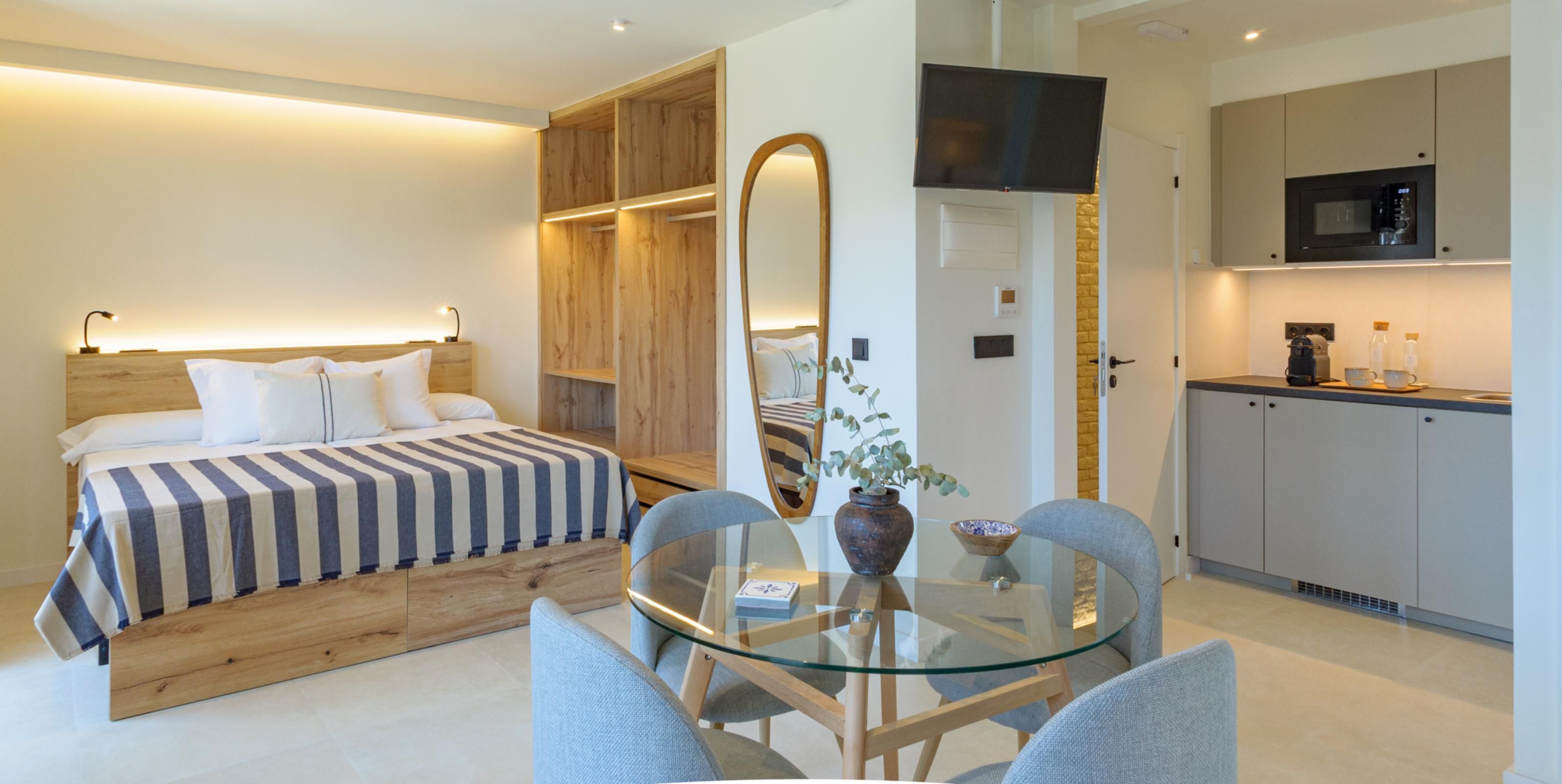 Una habitación de hotel moderna con una cama, una mesa de vidrio para comer y una kitchenette.