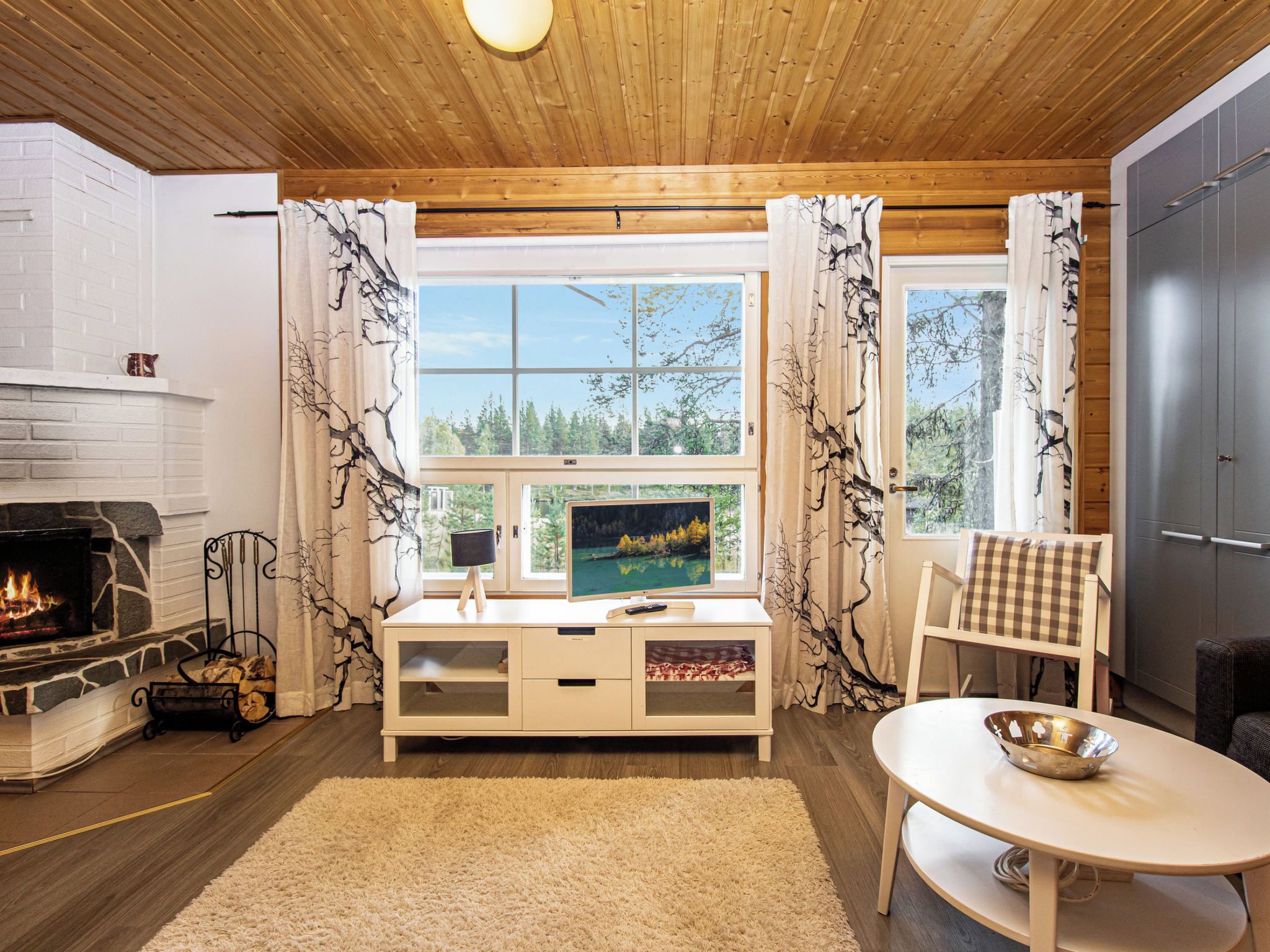 Una sala de estar acogedora con chimenea, televisor y vistas al exterior.