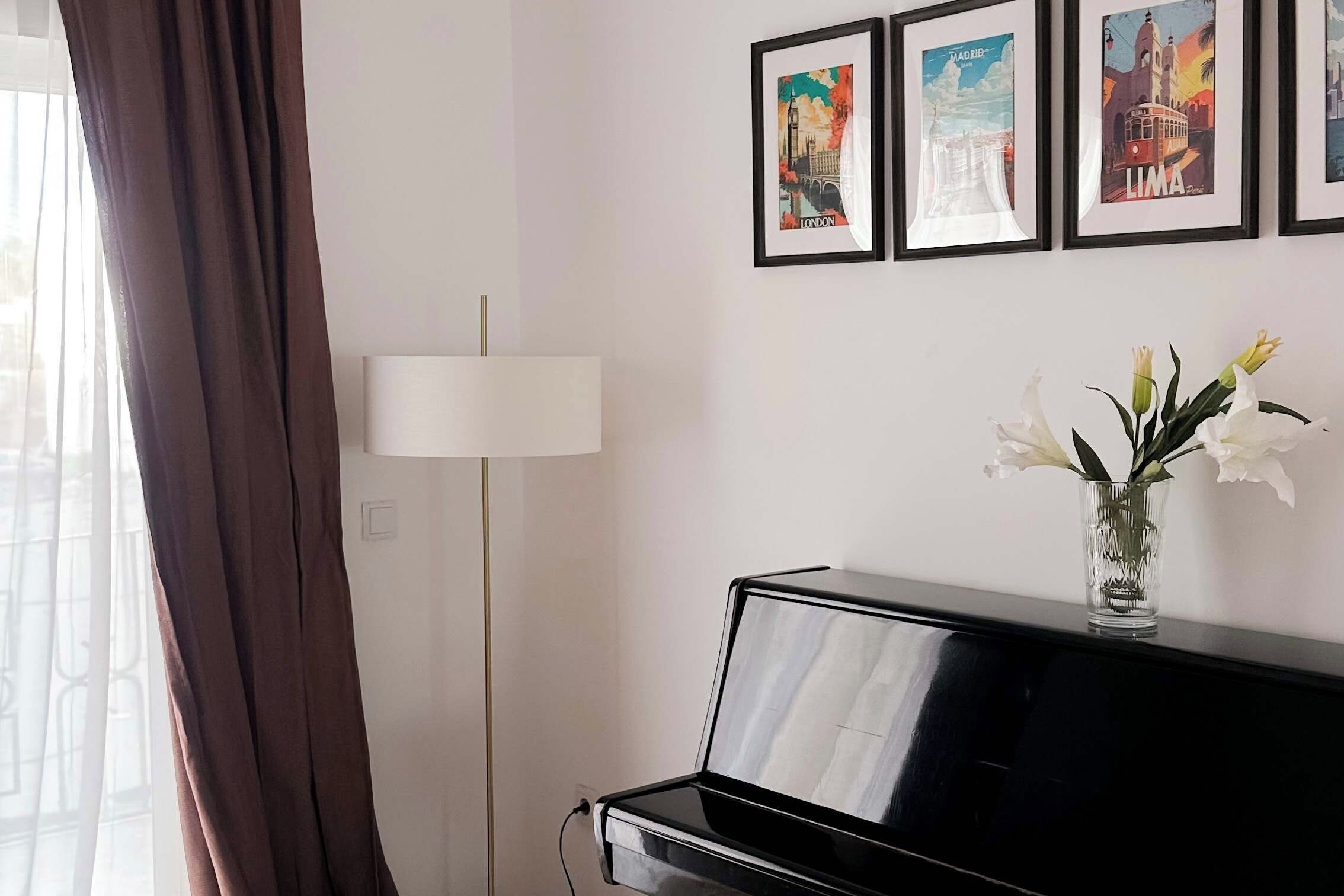 Una habitación con un piano, una lámpara y cuadros en la pared.
