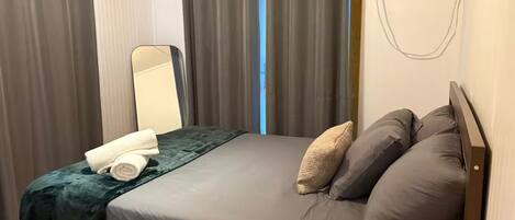 A bedroom with a bed, a mirror, and a wall-mounted air conditioning unit.