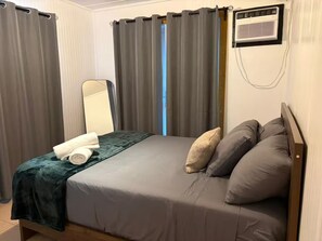 Un dormitorio con cama, espejo y aire acondicionado de pared.
