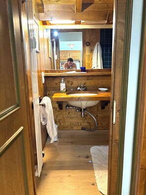 A wooden bathroom with a sink, mirror, and towel rack. - New Listing (Megève)