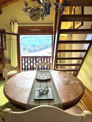 A wooden dining table with a placemat, a pair of glasses, and a decorative plate. A wooden chair is positioned in front of the table. - New Listing (Megève)