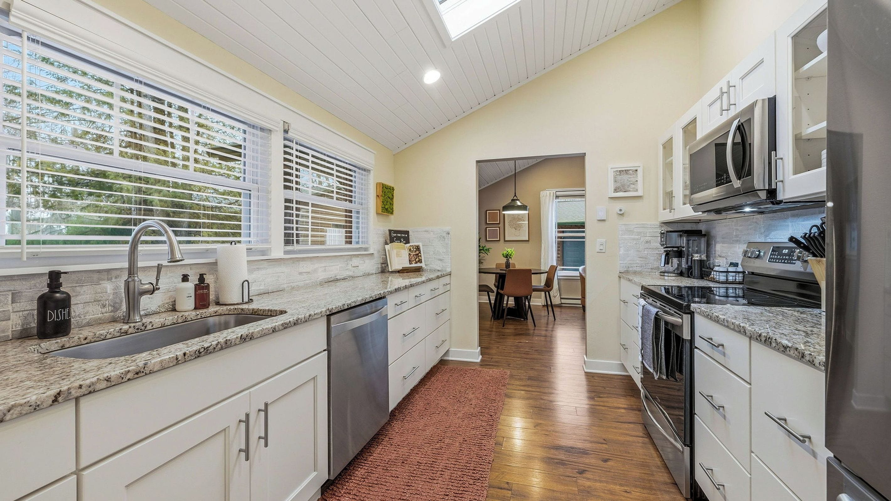 A modern kitchen with granite countertops, stainless steel appliances, and a dining area with a view of the outdoors.