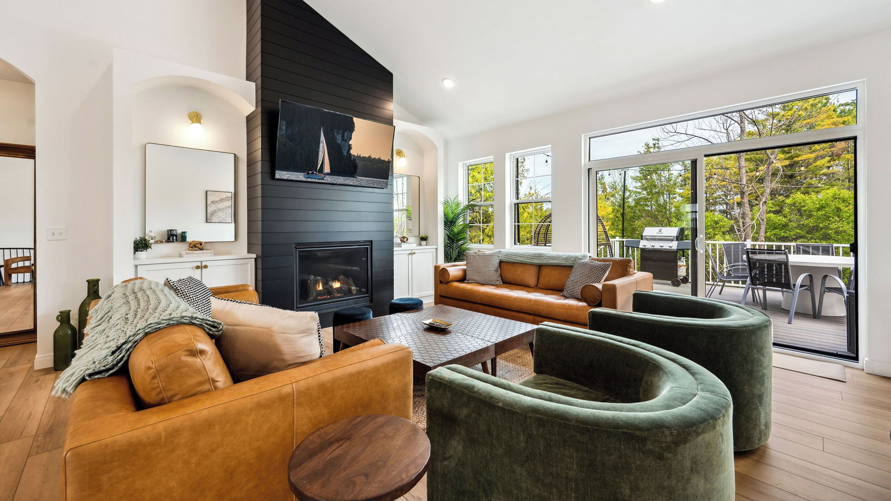 A modern living room with a fireplace, leather sofas, and a view of the outdoors.