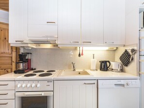 Una cocina moderna con armarios blancos, estufa, lavamanos y lavavajillas.