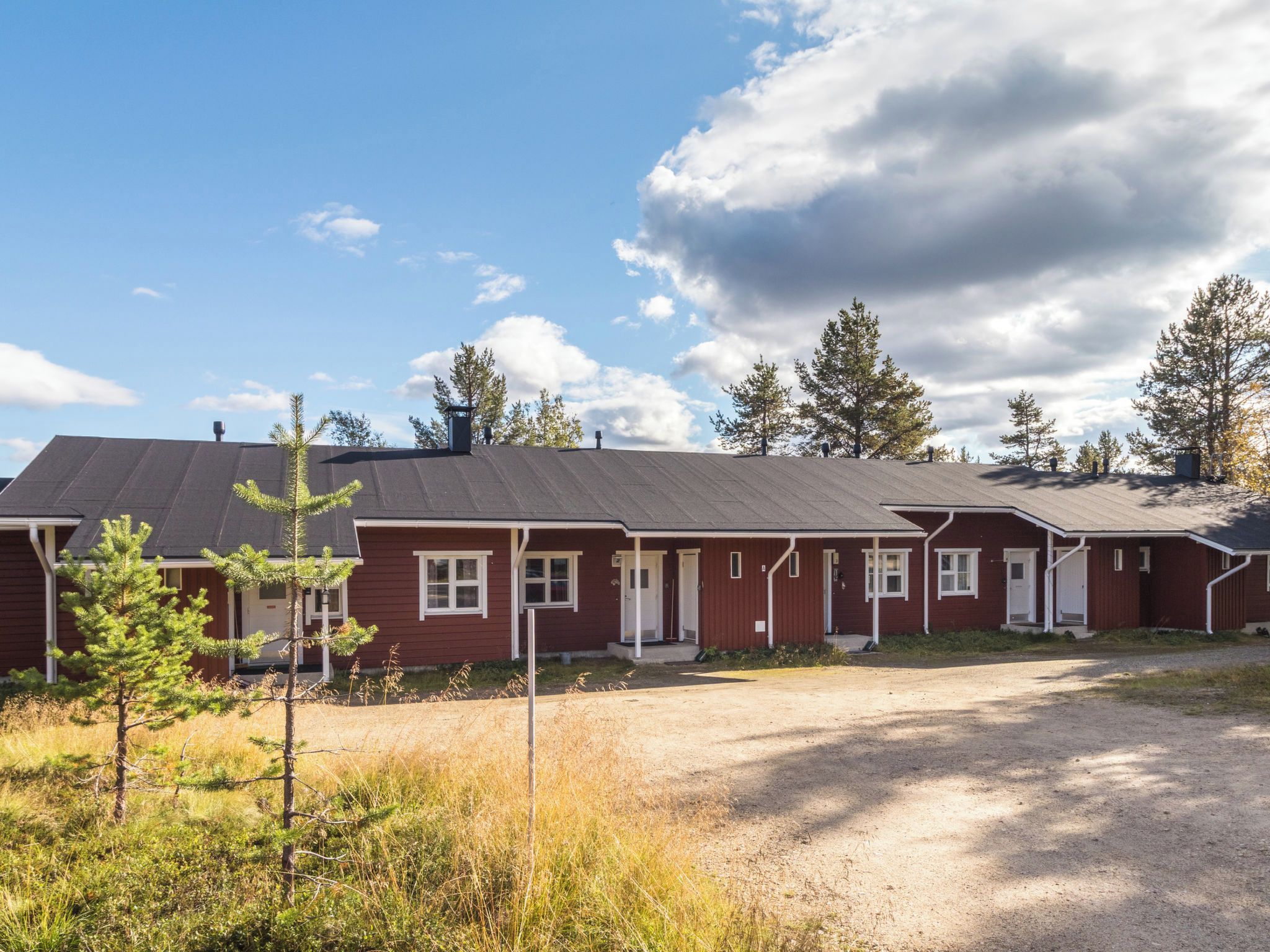 Rivi punaisia rakennuksia, joiden edessä on sorapäällysteinen ajotie ja niitä ympäröi niukasti kasvillisuutta.