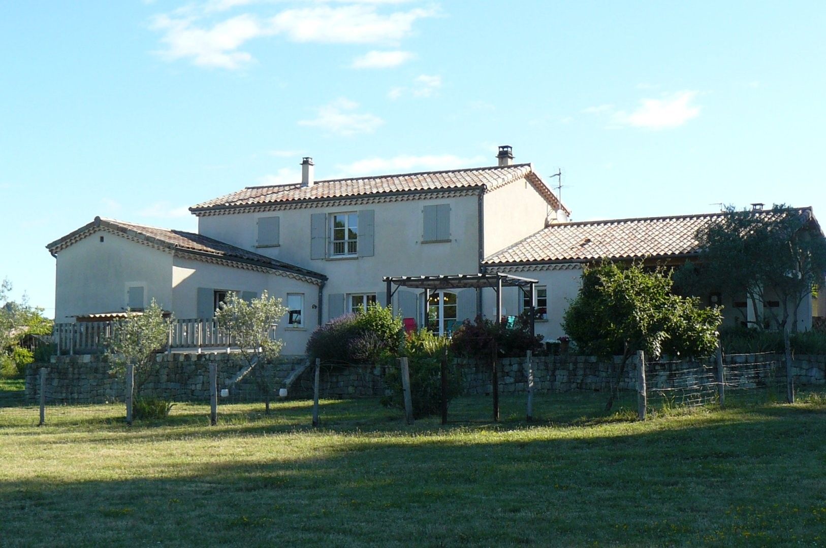 Ein zweistöckiges Haus mit Ziegeldach, Steinmauer und Rasenfläche.