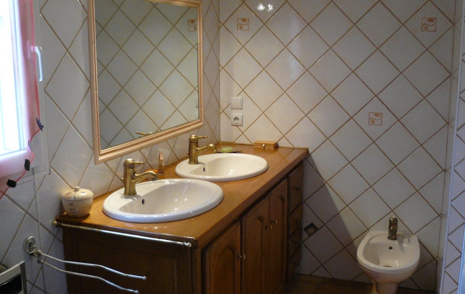 Un baño con dos lavamanos, un espejo y un bidé.
