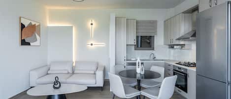 A modern kitchen with a Bosch refrigerator, a dining area with a round table and chairs, and a living area with a sofa and a coffee table.