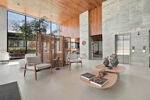 Ein modernes Interieur mit einer Sitzecke, einem Couchtisch mit Büchern und Blick ins Freie.