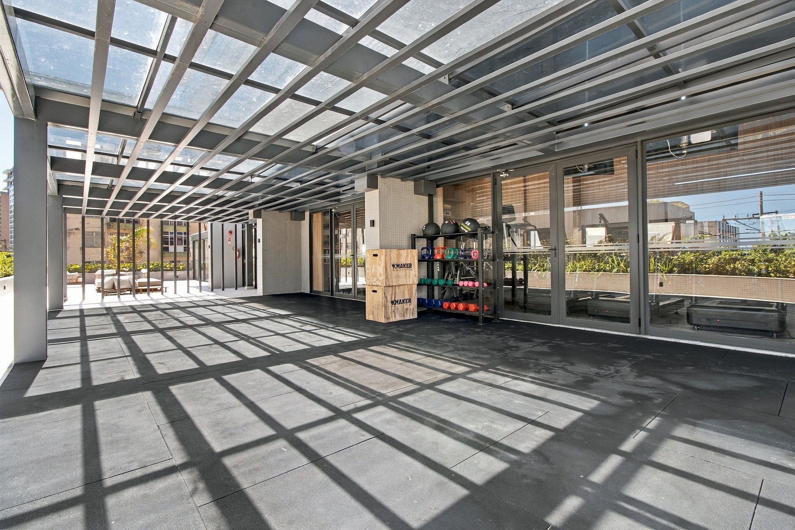 A spacious indoor area with a glass ceiling, a weightlifting station, and a seating area with a view of the outside.