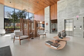 Um interior moderno com área de estar, mesa de centro com livros e vista para o exterior.