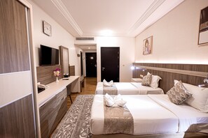 A hotel room with two beds, a desk, a TV, and a bathroom. - Romance Al-bait Hotel (makkah)