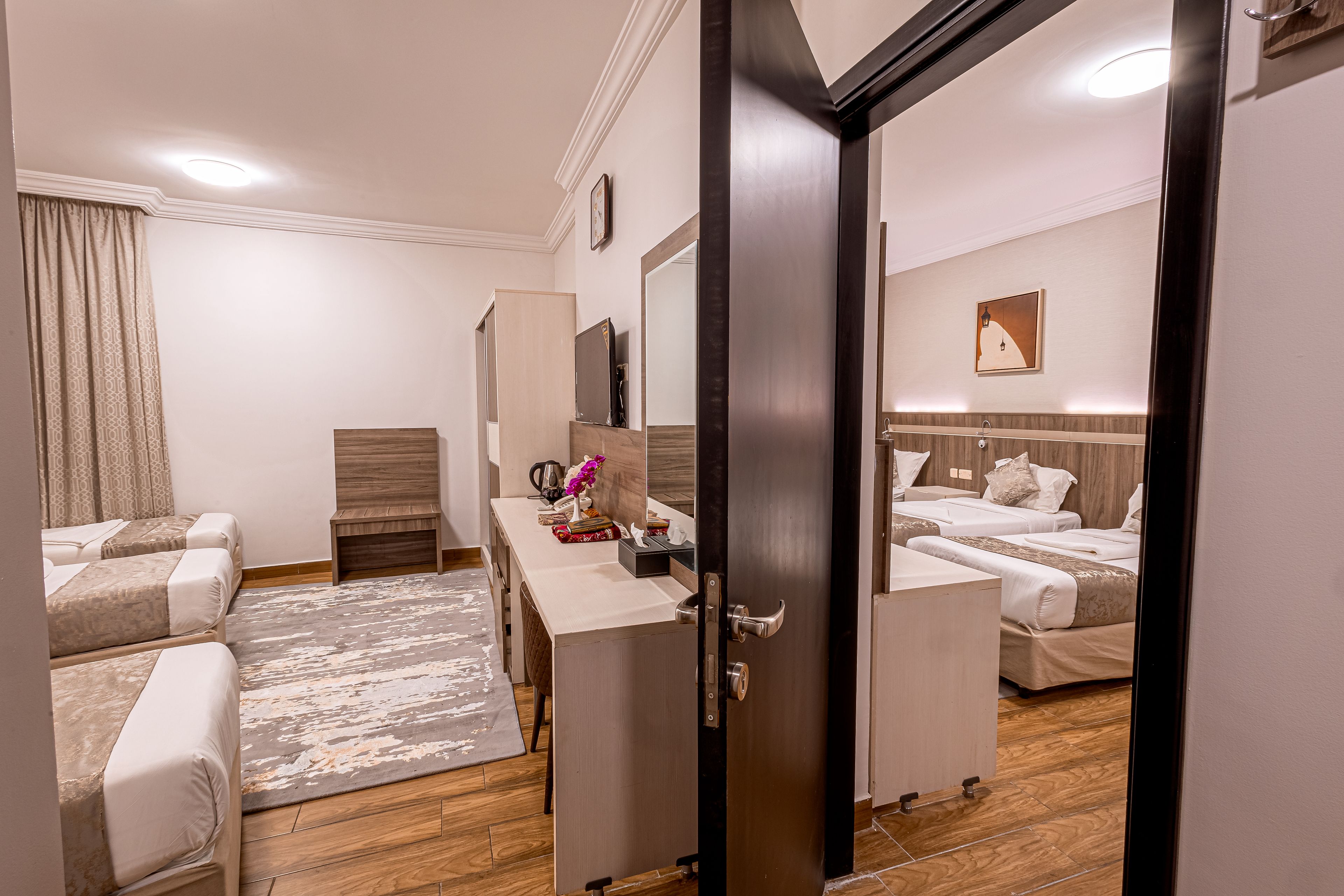 A hotel room with two beds, a desk, a wardrobe, and a bathroom.