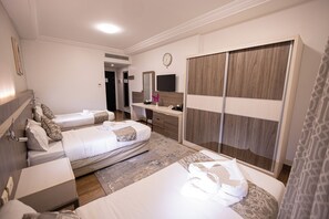 A hotel room with two beds, a desk, a wardrobe, and a television. - Romance Al-bait Hotel (makkah)