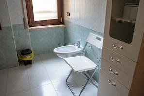 A bathroom with a sink, a mirror, and a small stool. - B&B 31mt dal Duomo (Benevento)