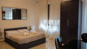 A hotel room with a bed, a desk, a wardrobe, and a mirror on the wall.