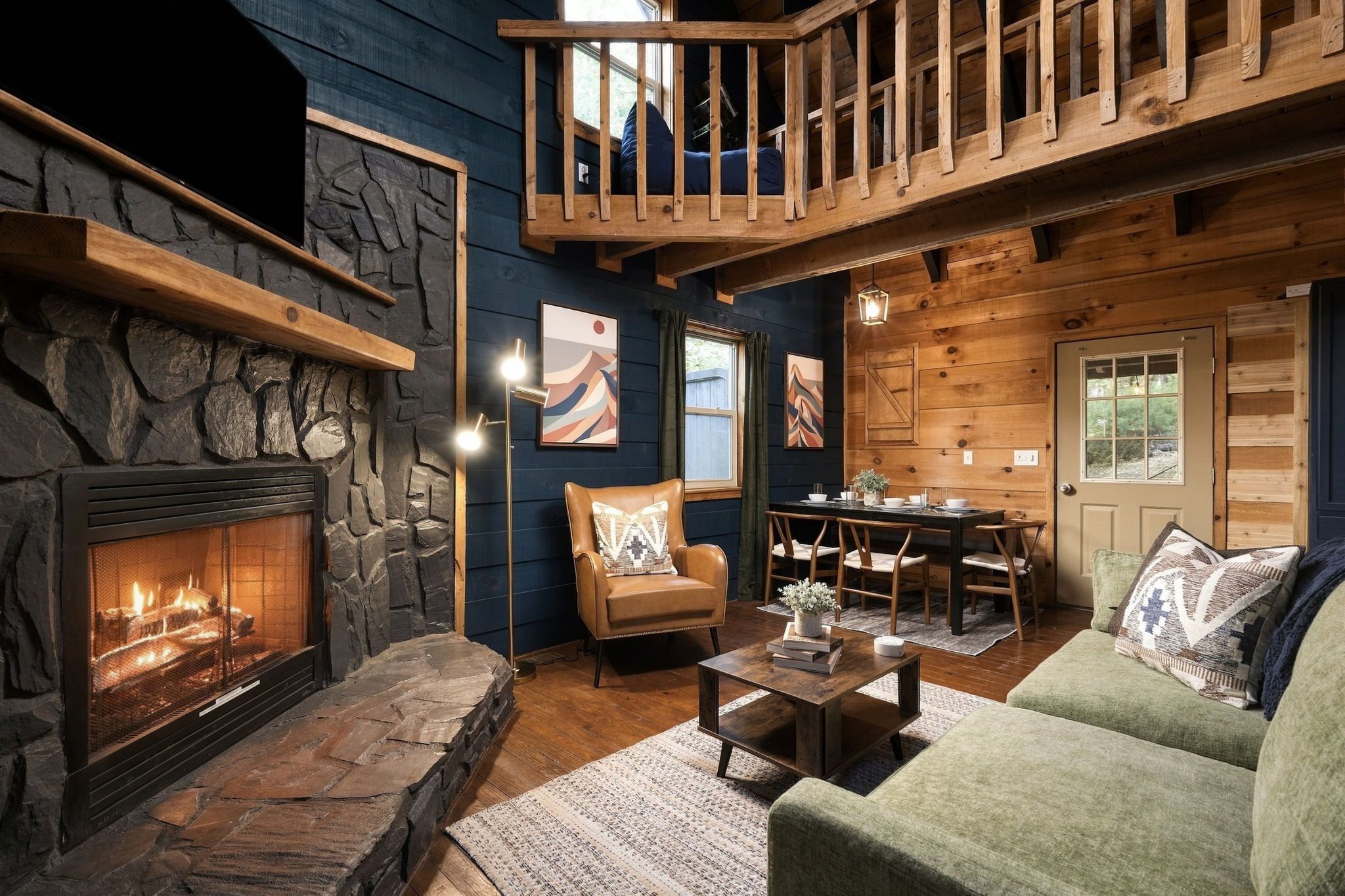 Un interior acogedor con chimenea de piedra, muebles de madera y un balcón.