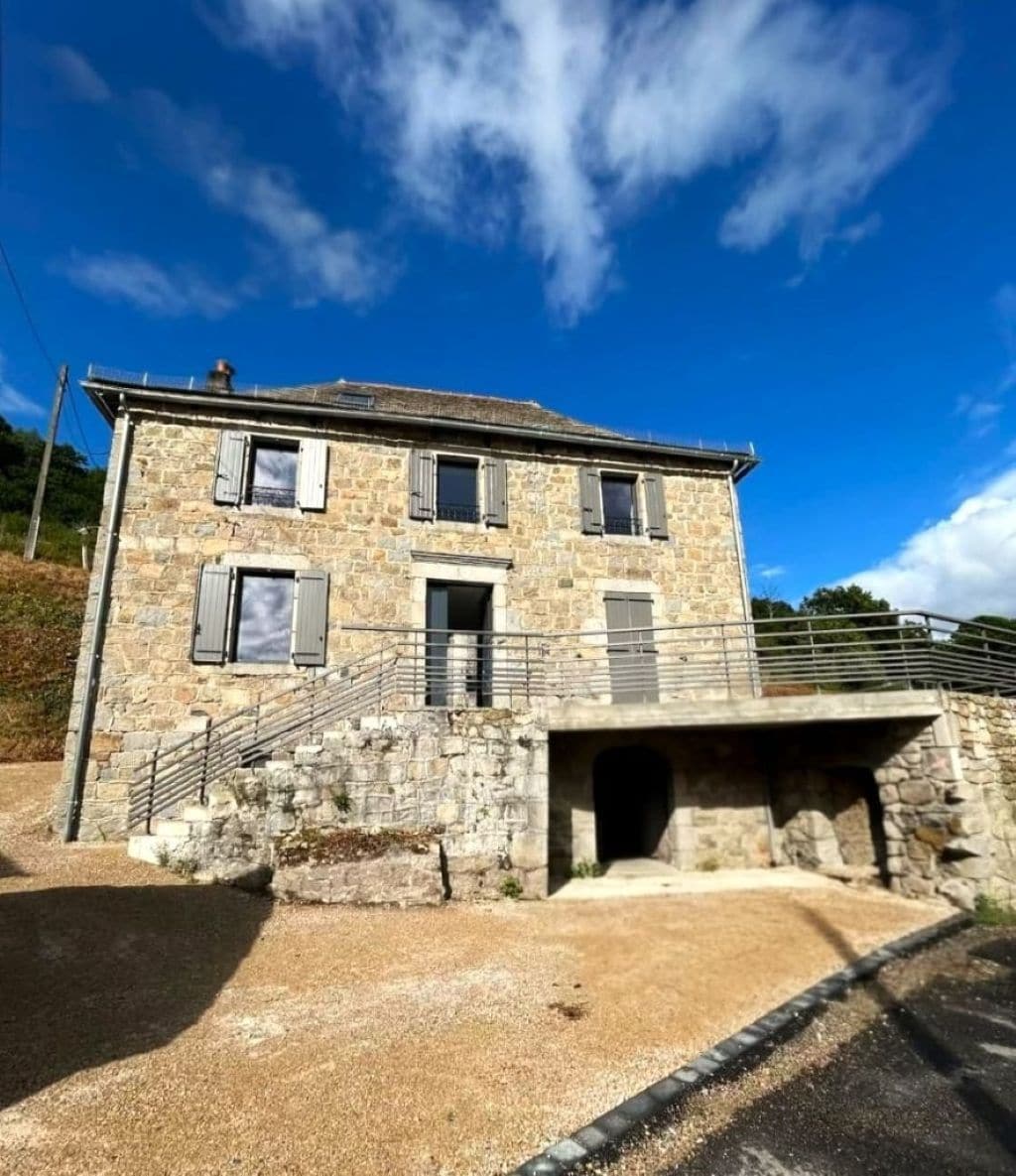 Un bâtiment en pierre avec un escalier menant à une porte, un petit balcon et une arche en pierre.