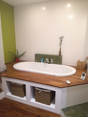 Ein Badezimmer mit freistehender Badewanne, einem Blumentopf, einer Shampooflasche und einem kleinen Korb.