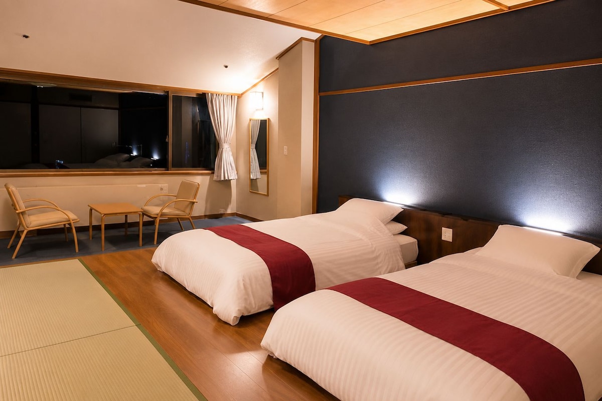 A hotel room with two beds, a desk, and a chair.
