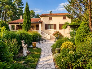 A two-story house with a stone pathway leading to a wooden deck.