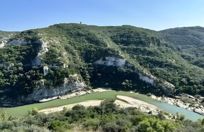 A mountainous landscape with a river, cliffs, and dense vegetation.