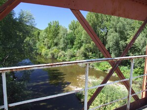 A metal bridge structure with a view of a river and dense greenery.