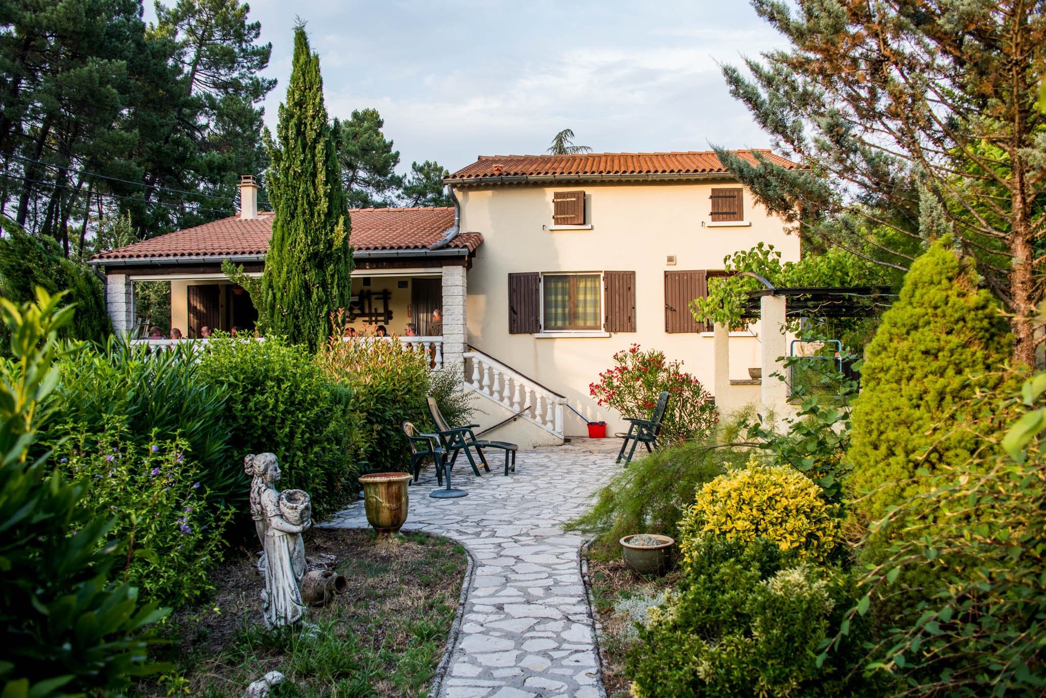 A garden pathway leading to a building with a tiled roof and a white facade.