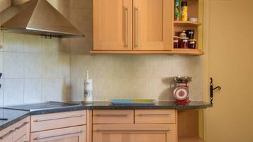 Eine Küche mit Holzausstattung, einer Edelstahl-Dunstabzugshaube, einer Waage und einem Gewürzregal.