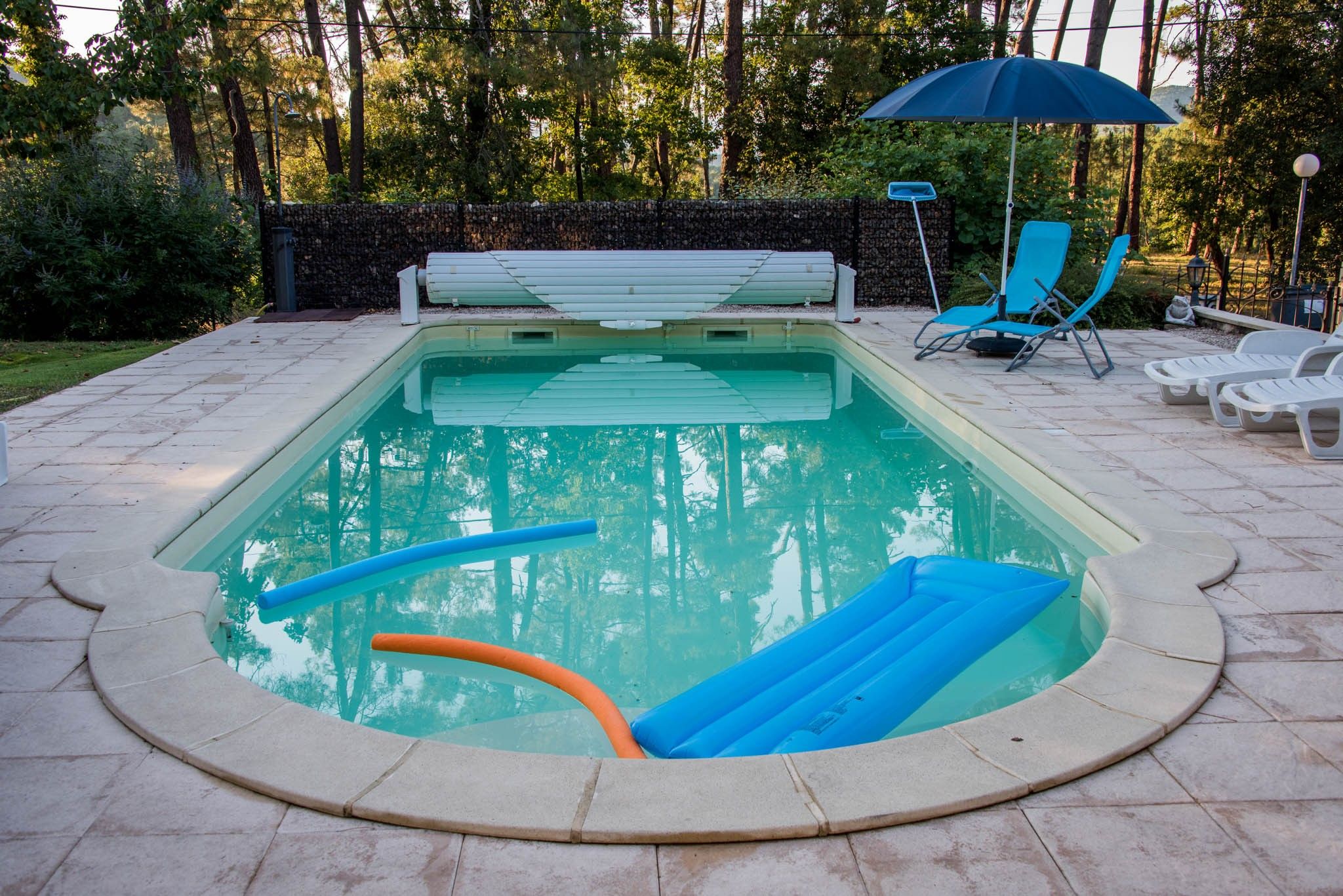 Ein Swimmingpool mit einer umlaufenden Sonnenterrasse, Liegestühlen und einer Sitzbank.