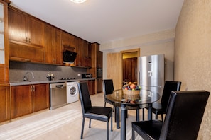 A modern kitchen with wooden cabinets, a stainless steel refrigerator, a dishwasher, and a dining table with chairs. - Marvelous 5-bedroom apartment with AC in charming Tbilisi (Tbilisi)