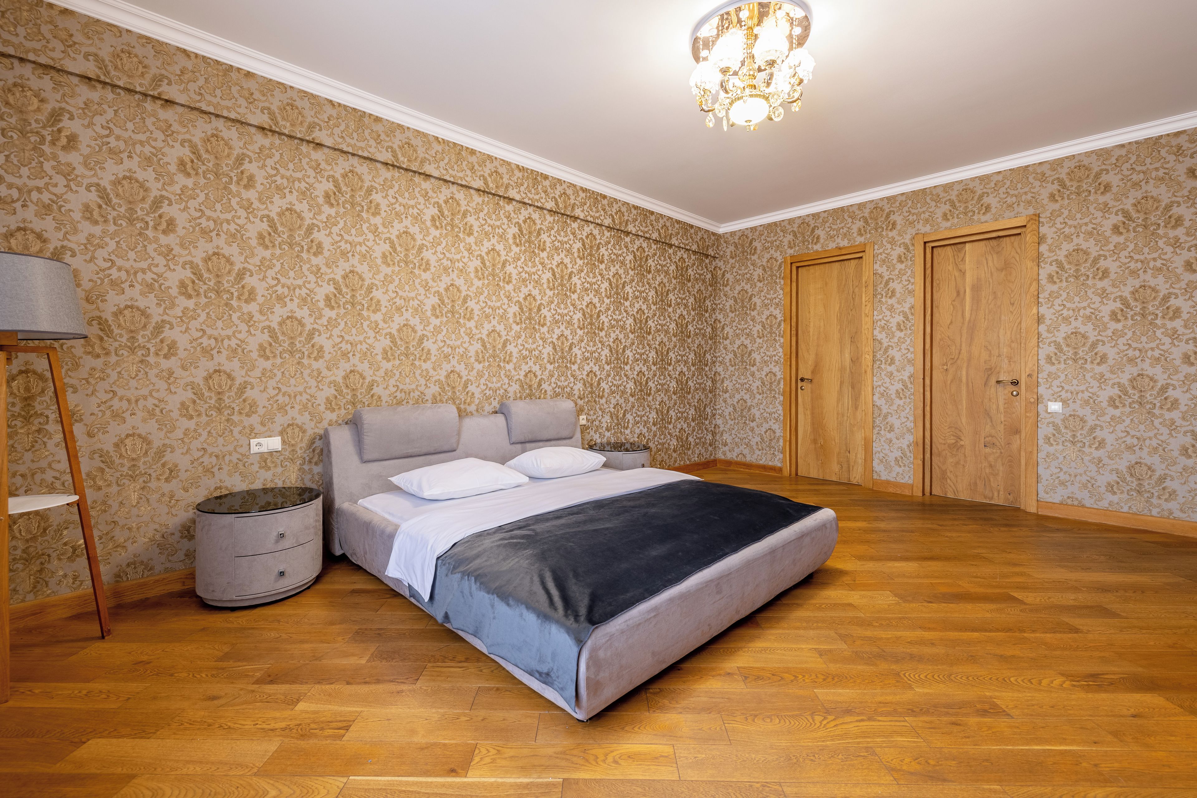 A bedroom with a bed, a nightstand, a lamp, and two doors.