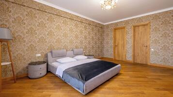 A bedroom with a bed, a nightstand, a lamp, and two doors.