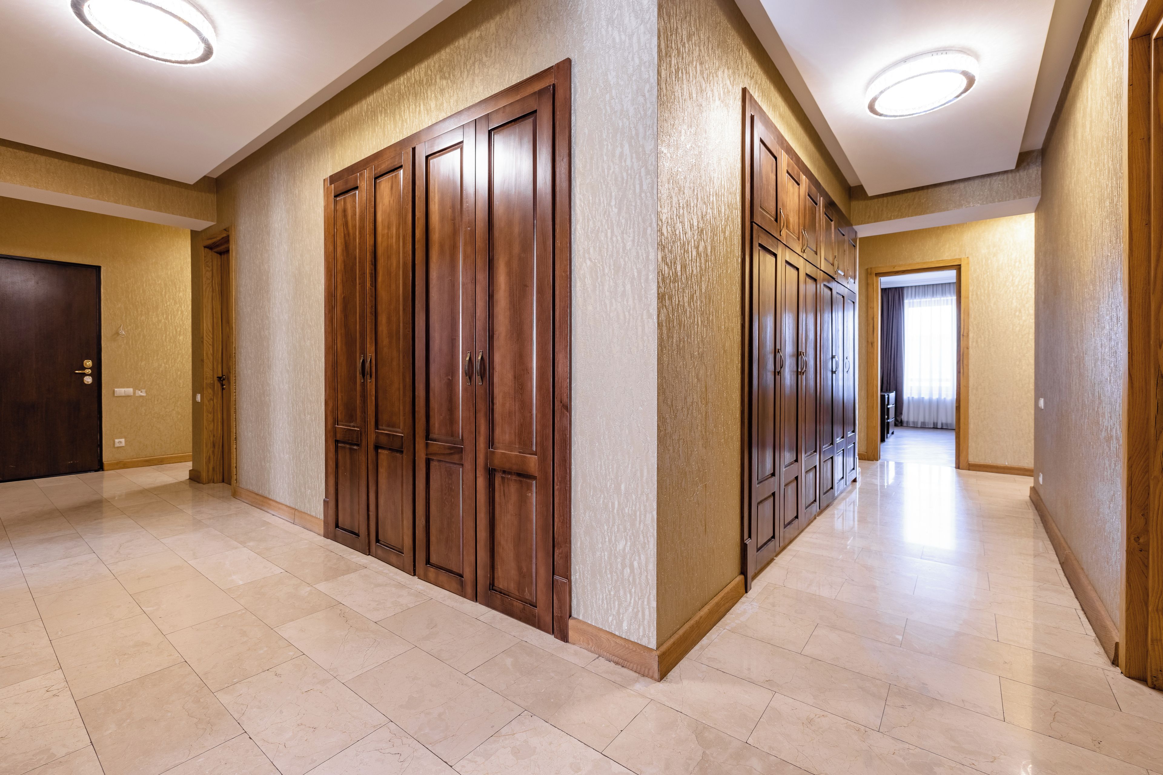 A spacious hallway with a series of wooden doors and a tiled floor.