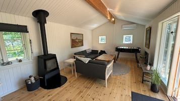 Uma sala de estar acolhedora com lareira a lenha, um sofá, uma mesa de centro e uma mesa de pebolim.