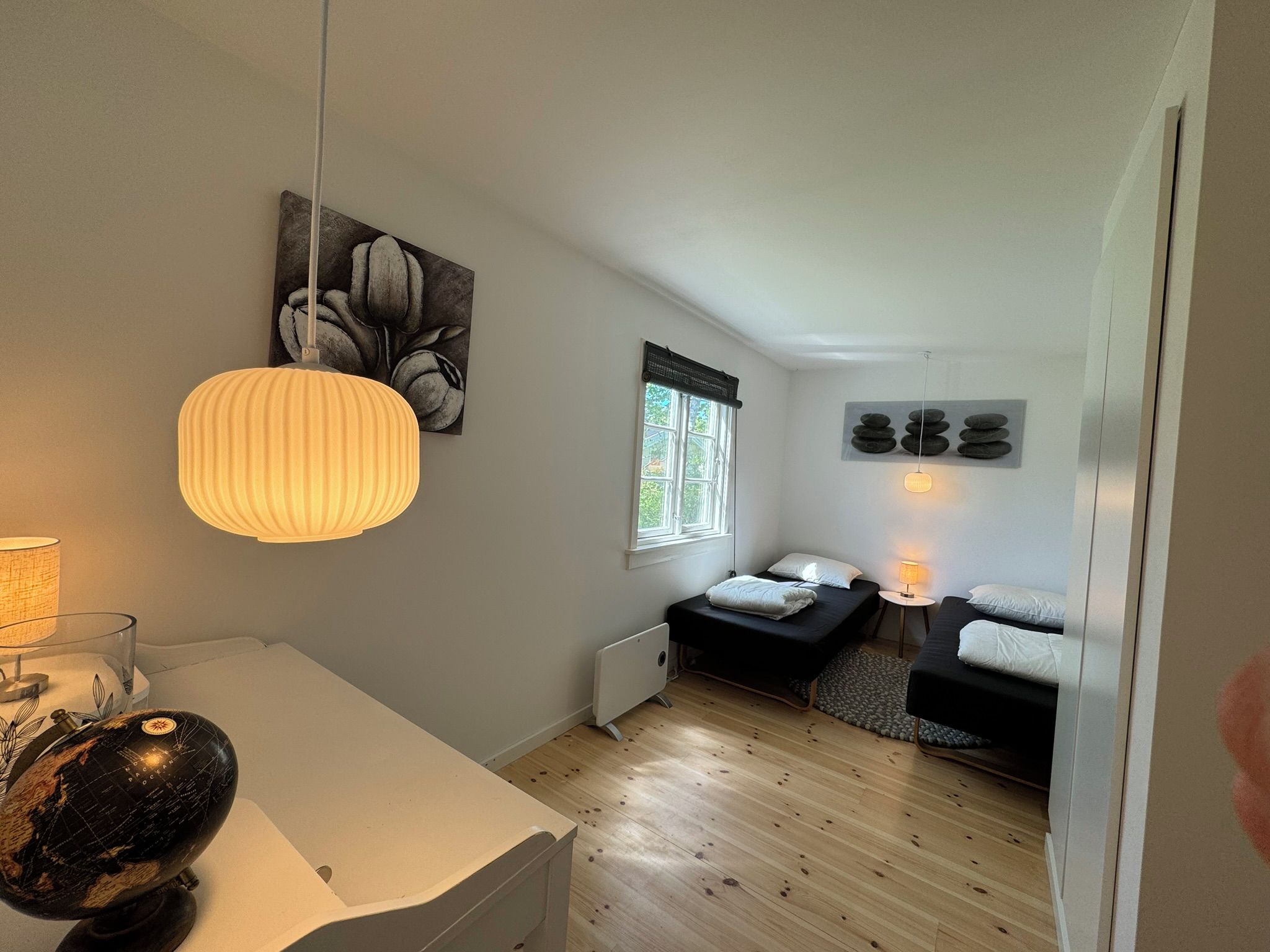 Quarto compacto com cama, mesas de cabeceira, um globo e janela.