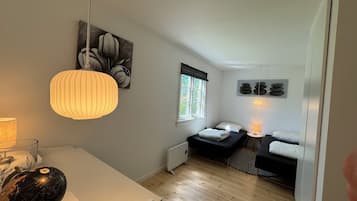 Quarto compacto com cama, mesas de cabeceira, um globo e janela.