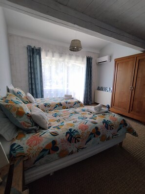 Une chambre avec deux lits, une armoire et une fenêtre avec des rideaux.