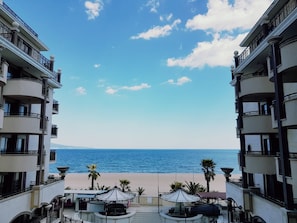 A hotel balcony with a view of the beach and the sea.