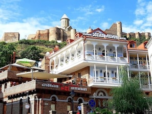 Hotel com varanda, restaurante e vista para as antigas fortificações ao fundo.