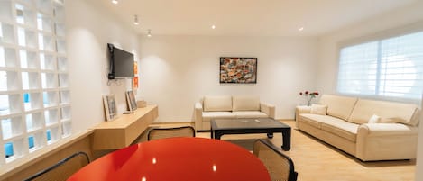 A modern living room with a sofa, a coffee table, and a TV mounted on the wall.