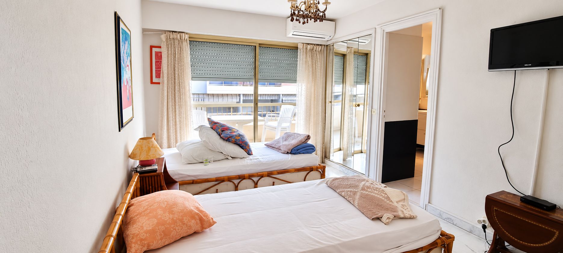 Habitación de hotel con dos camas, un televisor y una ventana con cortinas.