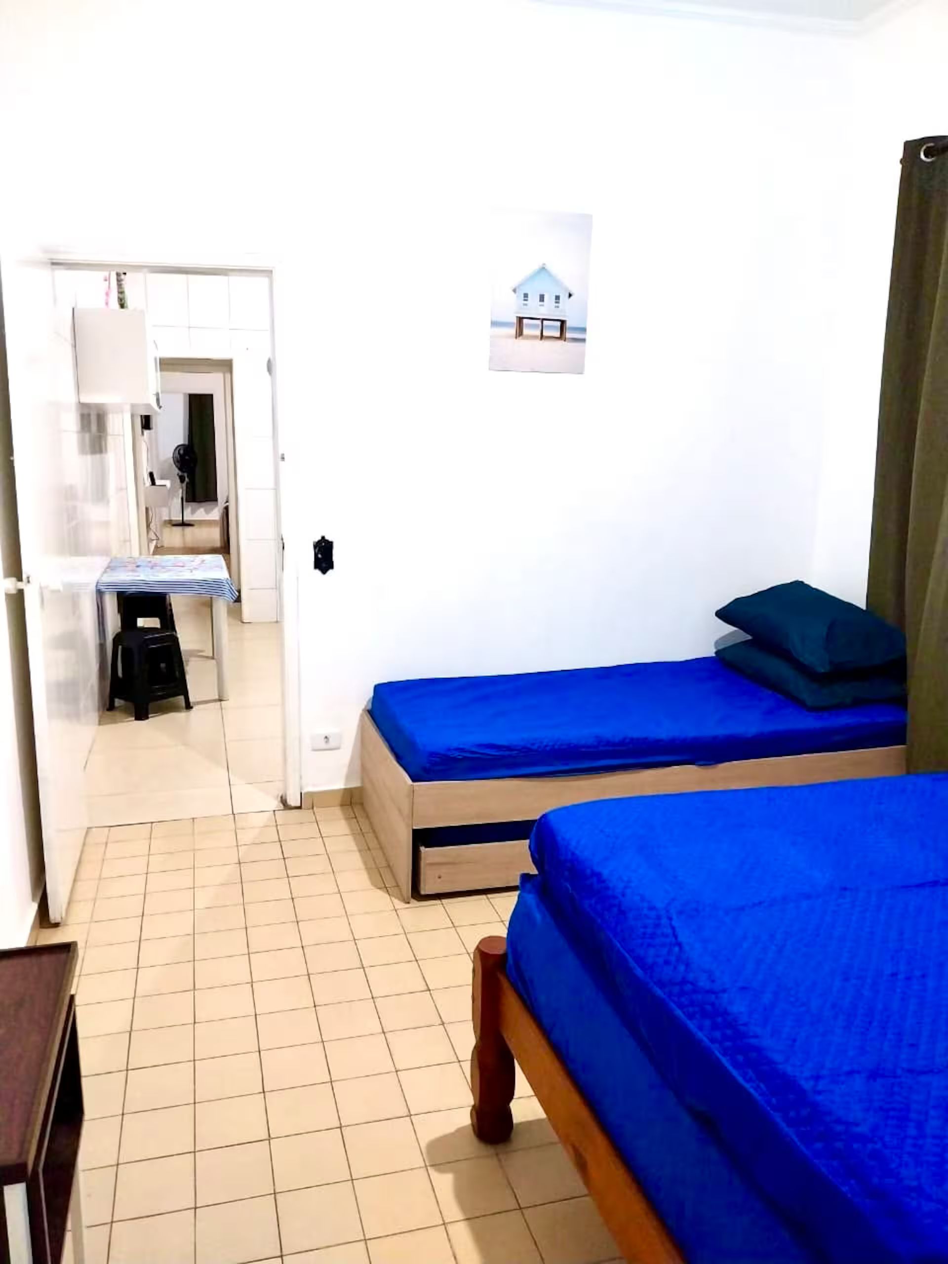 Una stanza con due letti, un tavolino e una sedia. Si apre una porta verso un'altra stanza.