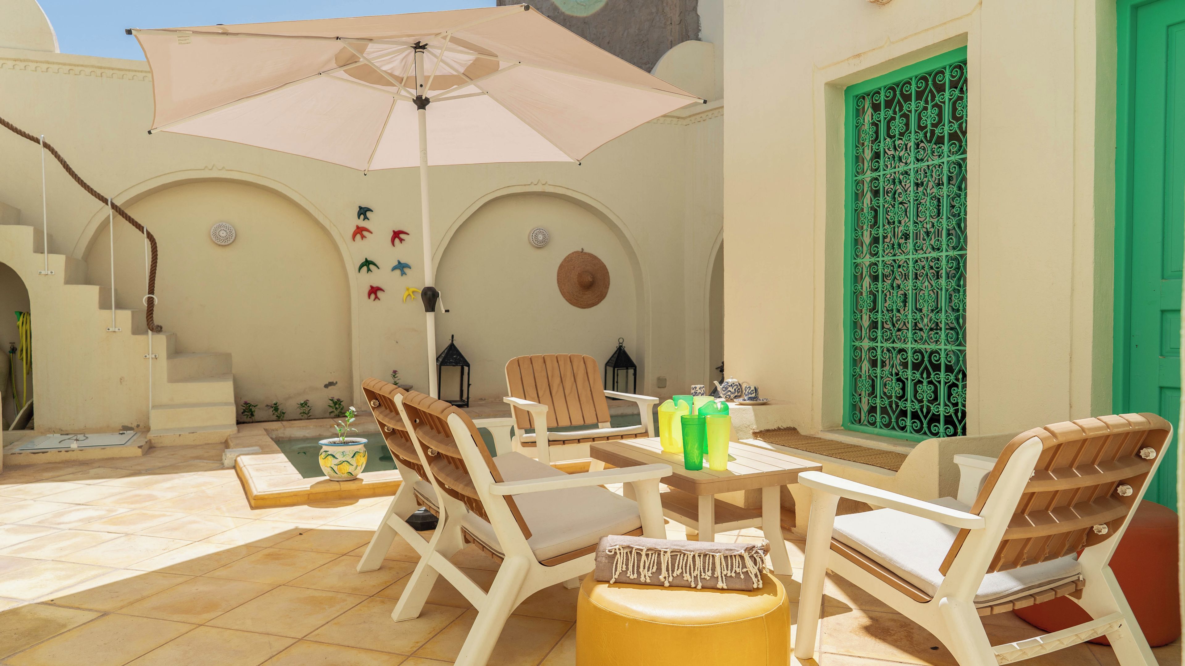 An outdoor seating area with a table, chairs, and a large umbrella.