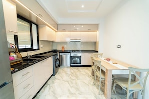 Una cocina moderna con horno empotrado, lavadora y comedor con mesa y sillas.